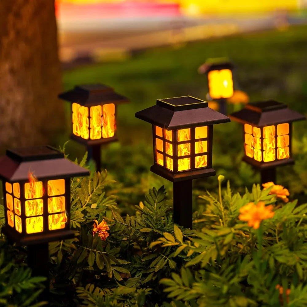 Decorative garden lanterns glowing warmly among flowers, enhancing nighttime outdoor ambiance.